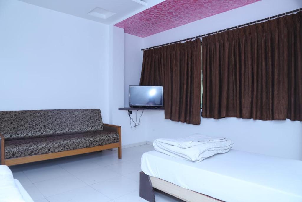JālgaonHotel Kewal INN的一间卧室配有一张床、一张沙发和一台电视。