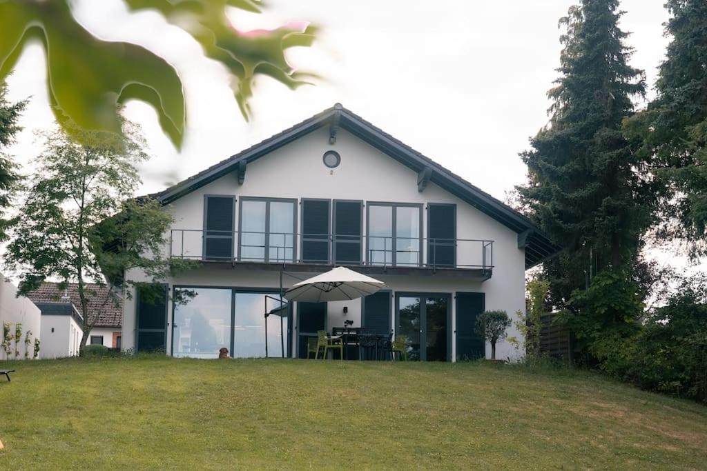 BleckhausenEifel21 - stilvolles Haus in der Vulkaneifel的带阳台和遮阳伞的白色房屋