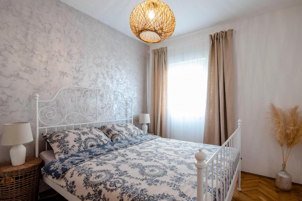 锡尼Apartman Karla的卧室配有白色的床和吊灯。