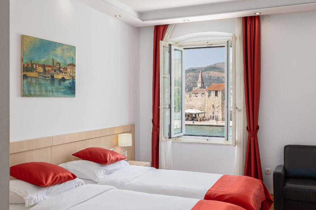 特罗吉尔Heritage Hotel Vila Sikaa的配有窗户的酒店客房内的两张床