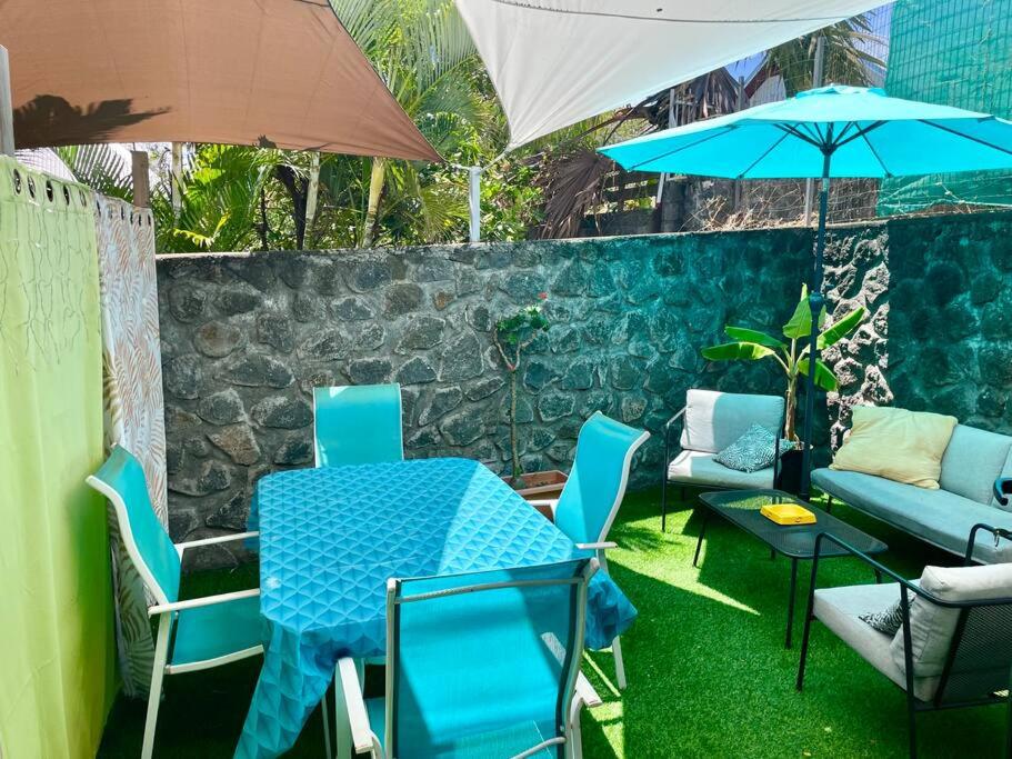 圣皮埃尔Beau logement en rez de jardin / terrasse privée / plage et ville à pied的一张桌子和椅子,配有蓝色的桌子和雨伞
