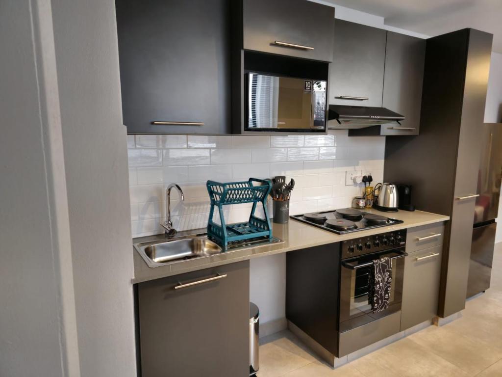 比勒陀利亚Circa Aparthotel - 1 Bedroom Apartment - close to Menlyn的厨房配有黑色橱柜和水槽