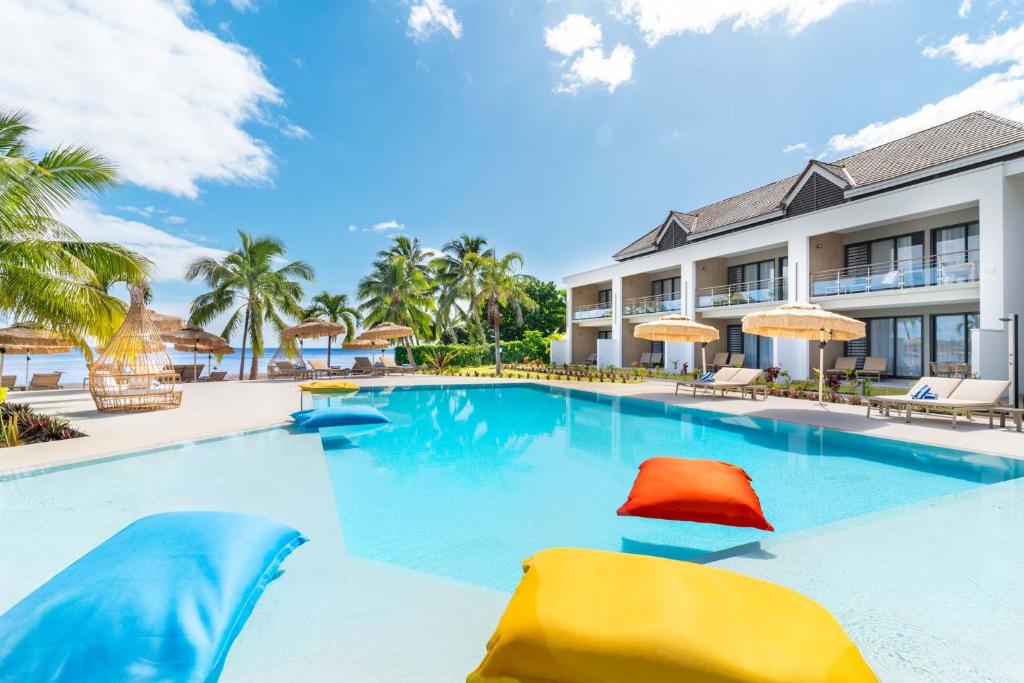 PaopaoCook's Bay Hotel & Suites的度假村的游泳池,配有椅子和遮阳伞