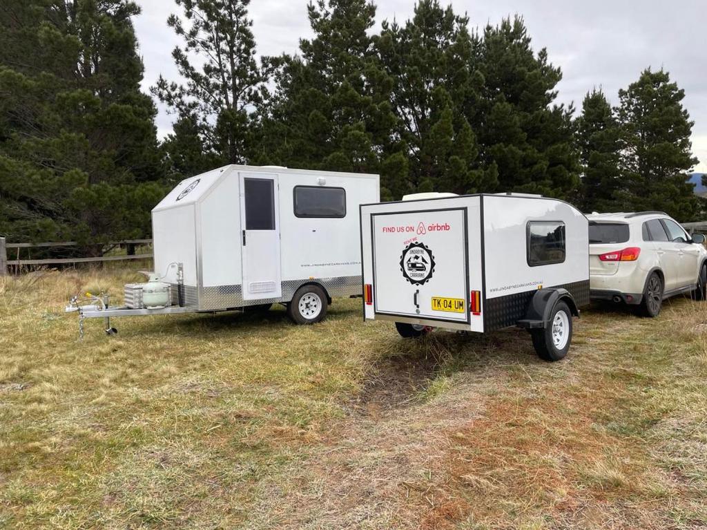 金德拜恩Jindabyne caravan hire的停在田野里的拖车和野营车