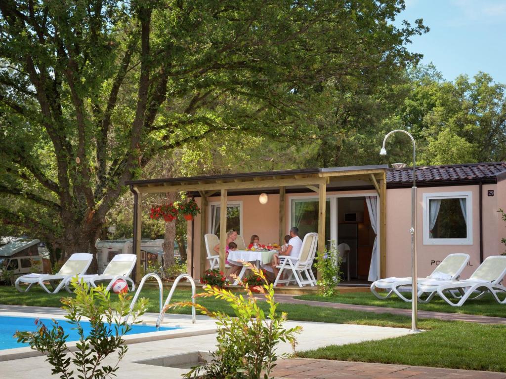 弗尔萨尔Modern chalet with 2 bathrooms的坐在泳池旁凉亭桌子旁的家庭