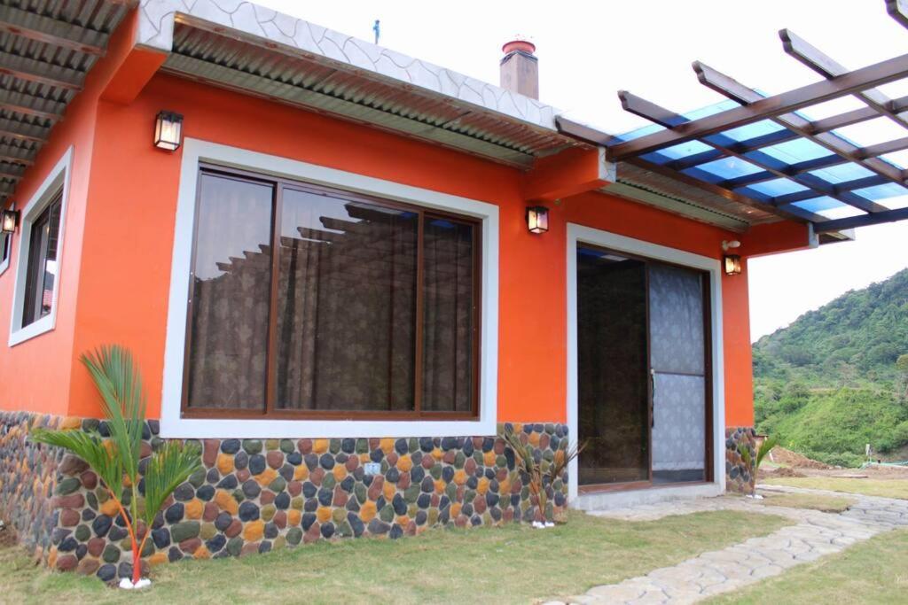 圣卡洛斯Casa Cabaña En San Carlos Panamá的一座橙色的房子,前面有一面岩石墙