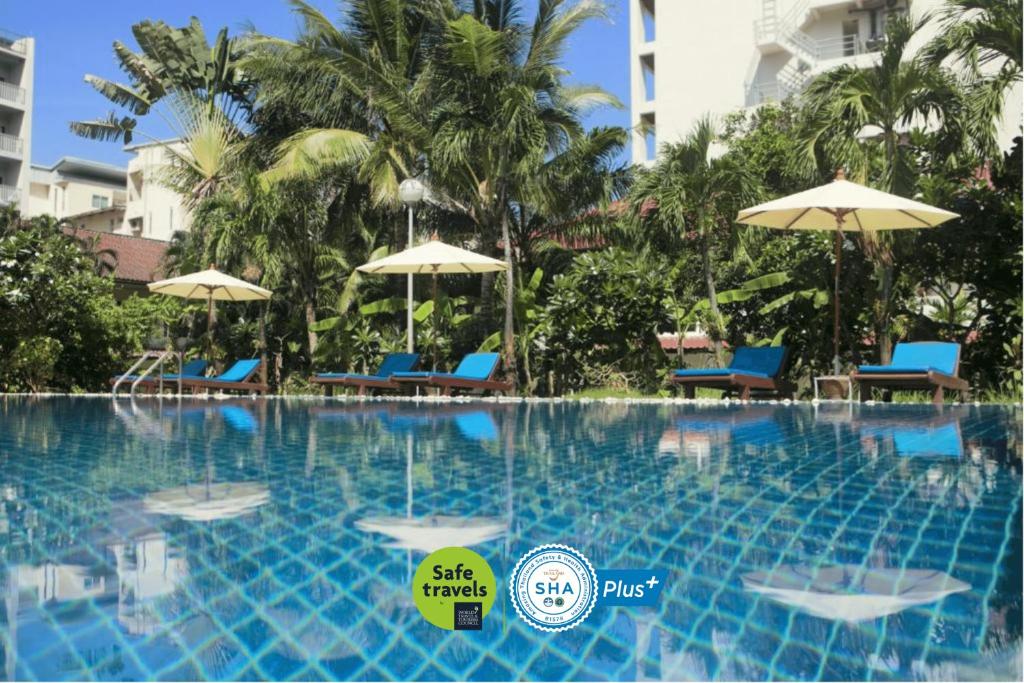 芭东海滩Patong Palace Hotel - SHA Extra Plus的度假村的游泳池,配有椅子和遮阳伞
