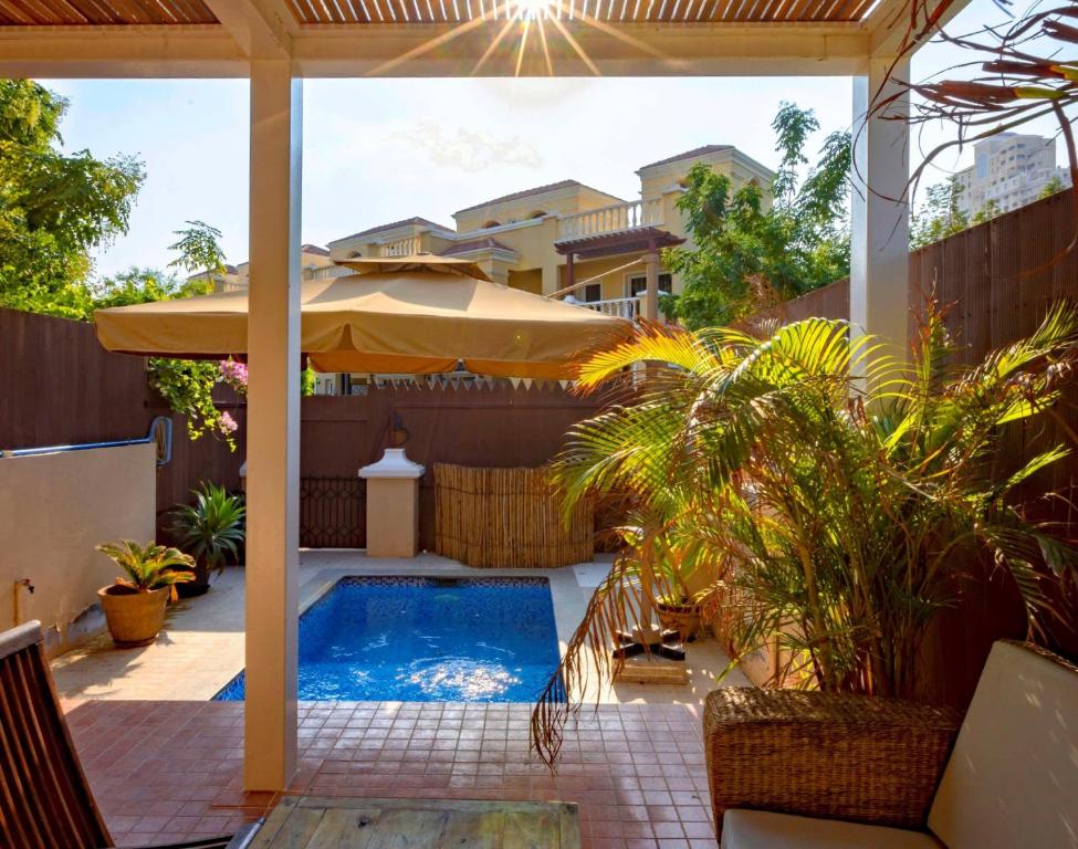 拉斯阿尔卡麦Dar 66 Plunge Pool Resort Townhouses的一个带游泳池和遮阳伞的庭院