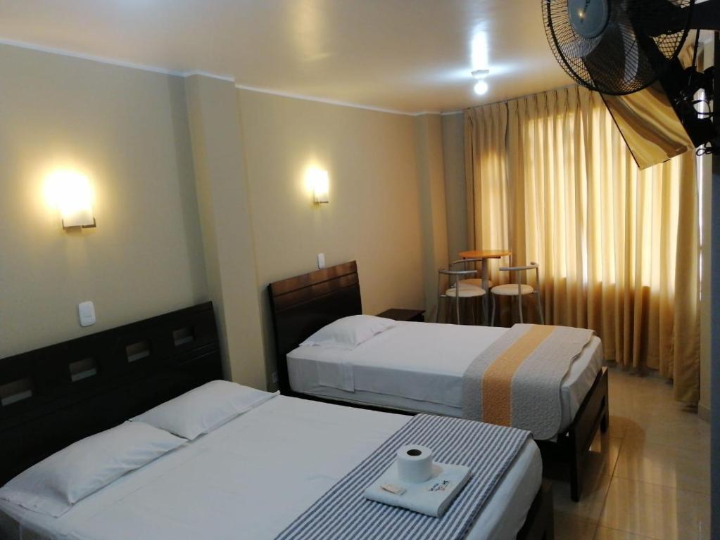 皮斯科HOSTAL LA NOCHE - Pisco的酒店客房设有两张床和一张桌子。