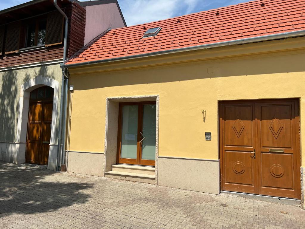 佩奇Aradi 6 Apartman Pécs的一座有两扇门和红色屋顶的建筑