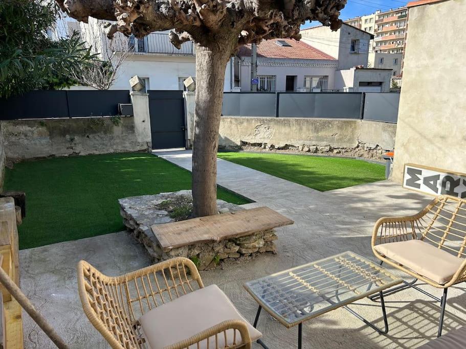 蒙彼利埃Villa proche centre Montpellier的庭院设有两把椅子和一张桌子,还有一棵树