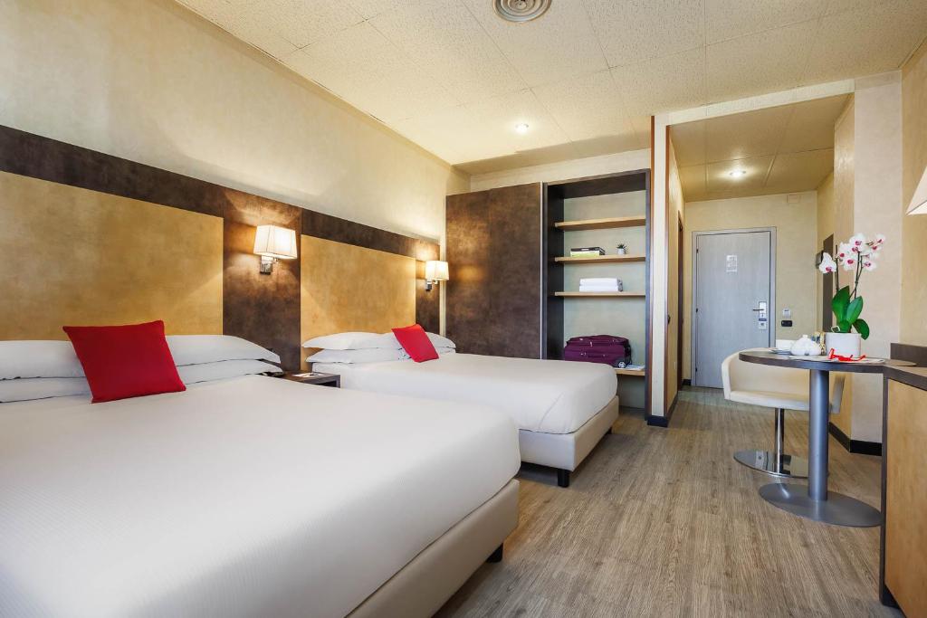 博洛尼亚JR Hotels Bologna Amadeus的酒店客房设有两张床和一张桌子。