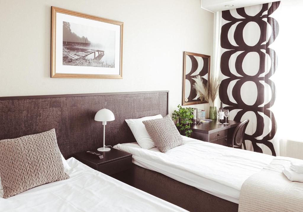 海门林纳艾米利亚酒店的配有白色床单的酒店客房内的两张床