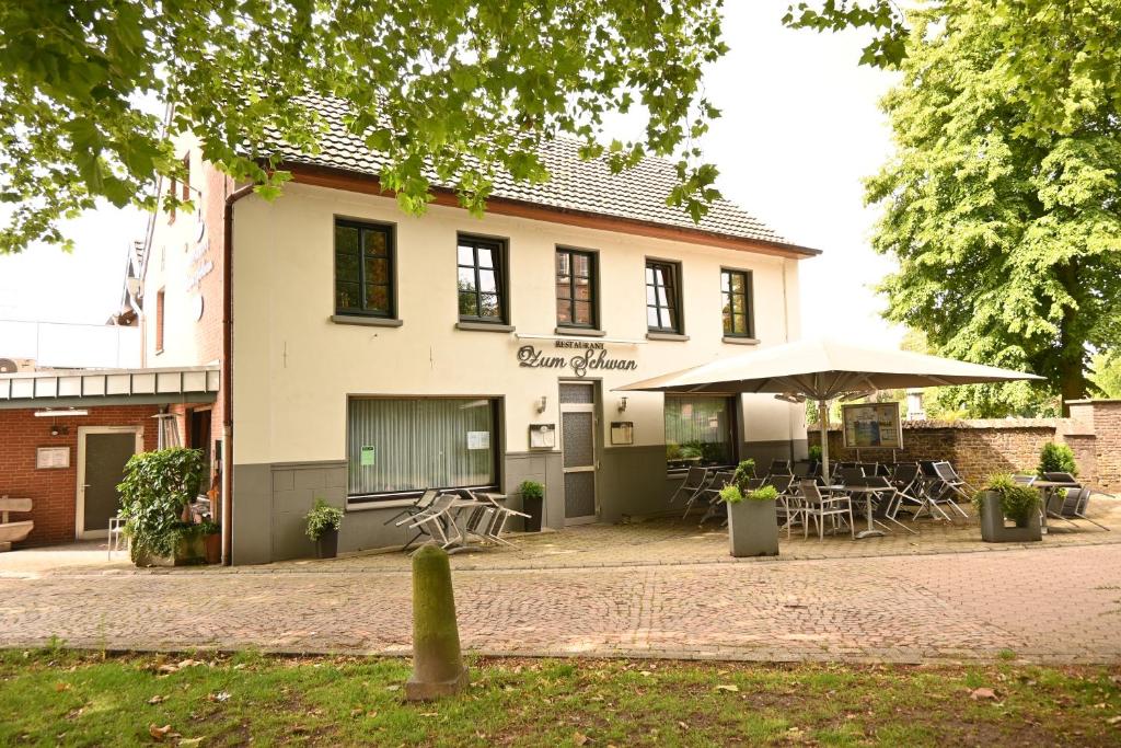 戈赫Hotel Restaurant Zum Schwan的一座配有桌椅和雨伞的建筑