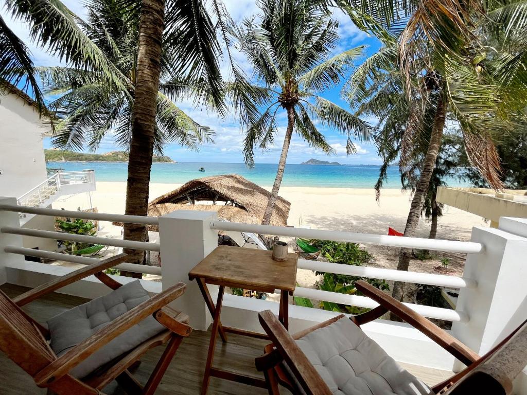 Song CauLucky Spot Beach Bungalow的一个带桌椅和海滩的阳台
