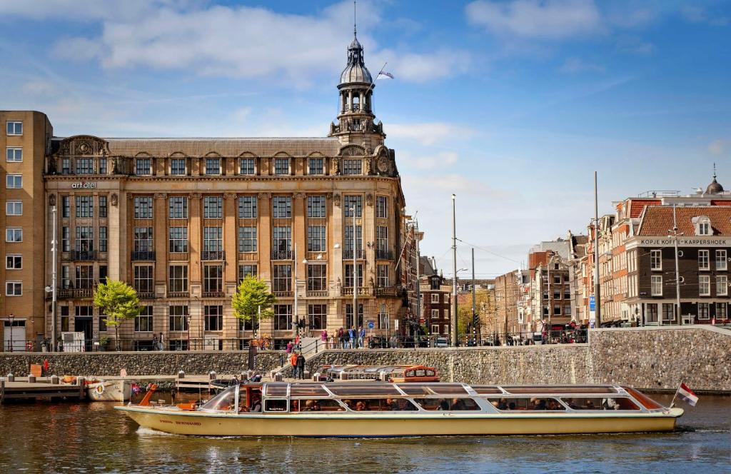 阿姆斯特丹art'otel amsterdam, Powered by Radisson Hotels的两艘船在水中,在建筑物前