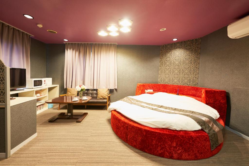 ホテル　モモ的一间卧室配有一张红色的大床和一张桌子