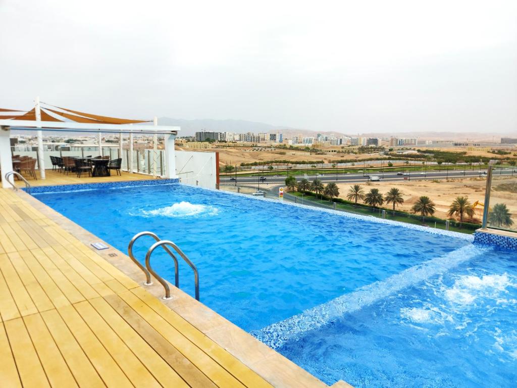 马斯喀特卡内连荣耀鲍尔酒店的一座大型蓝色游泳池,位于一座建筑的顶部