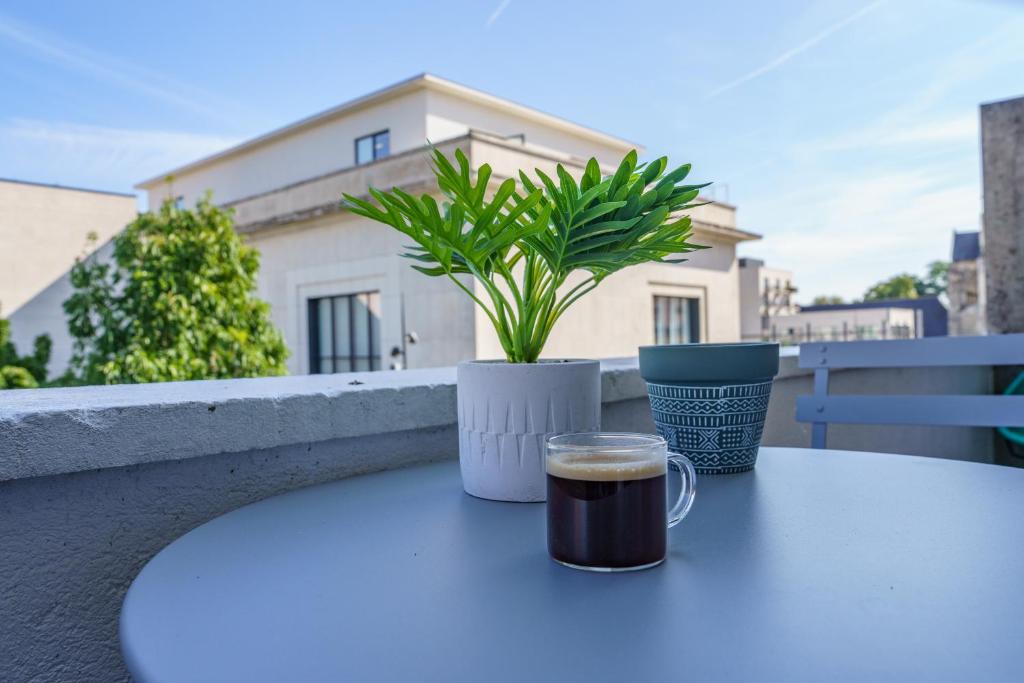 图尔Le Balcon des Arts - PrestiPlace Tours的桌上的咖啡和盆栽植物