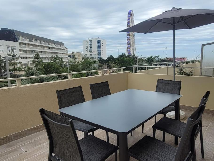 滨海贝尔克Appartement familial terrasse vue mer avec parking的阳台配有桌椅和遮阳伞