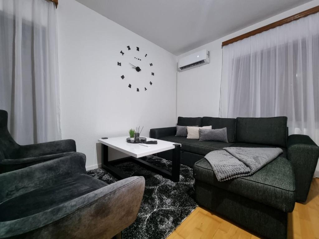 Sanski mostGOLD Apartman的带沙发、椅子和时钟的客厅