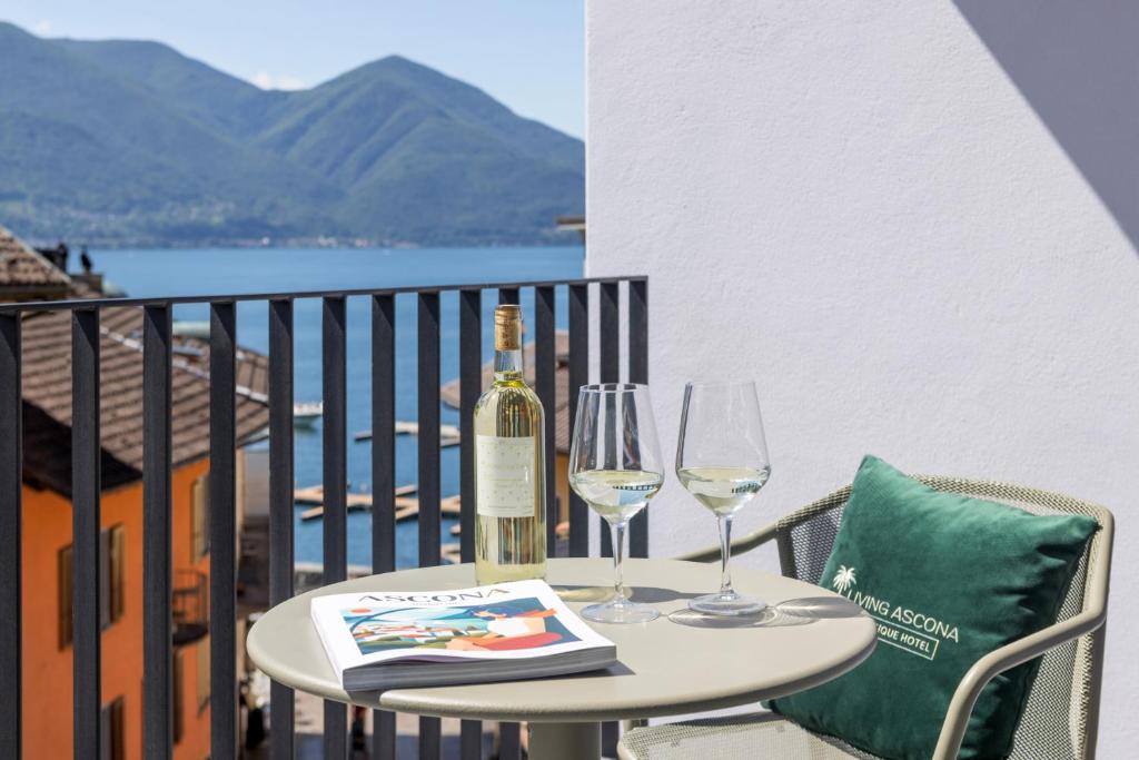 阿斯科纳Living Ascona Boutique Hotel - Smart Access的一张桌子,上面放着两杯酒和一瓶葡萄酒