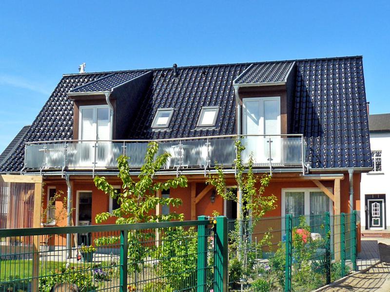 KröslinFerienwohnungen mit Balkon的一座带黑色屋顶和围栏的房子