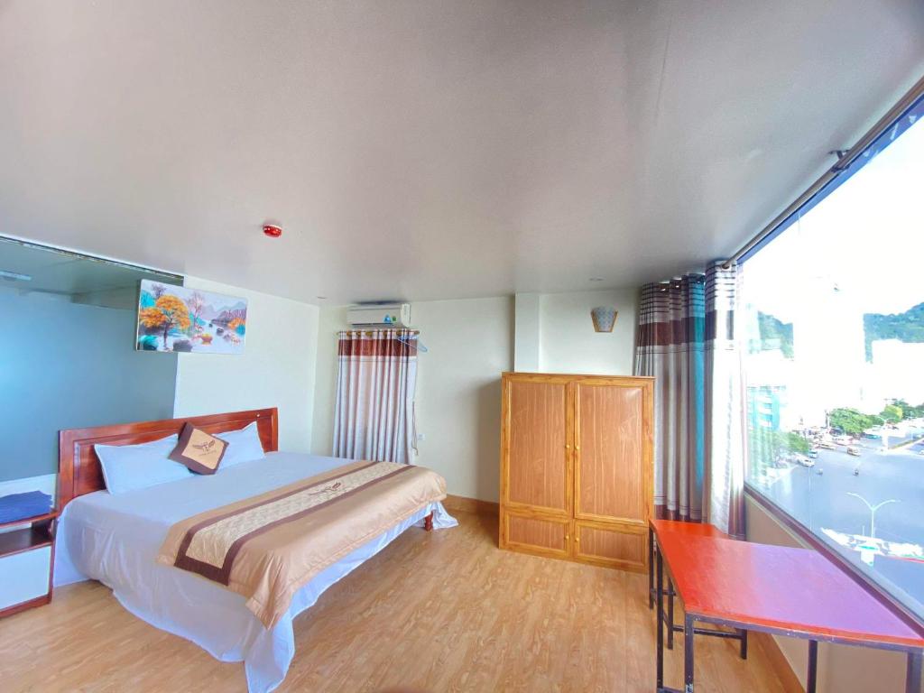 吉婆岛Cat Ba Victory Hostel的一间卧室配有一张床、一张书桌和一个窗户。
