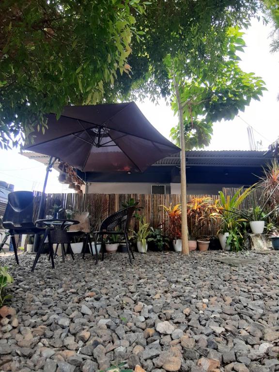 科隆Elisha's Guest House的庭院设有桌子和一把位于岩石上的遮阳伞