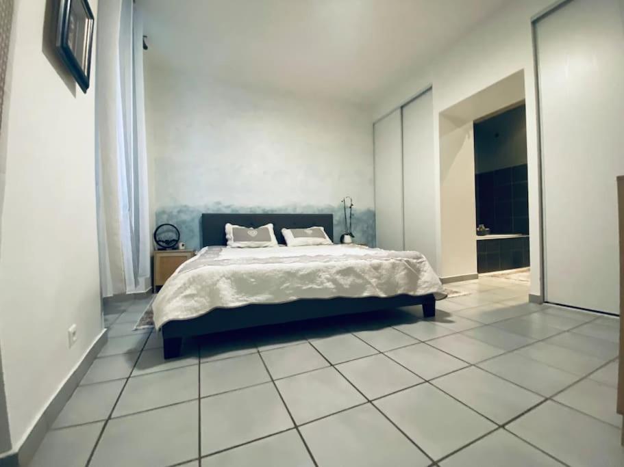 格拉斯Spacieux 3 pièces avec terrasse - Parking的卧室配有1张床,铺有瓷砖地板。