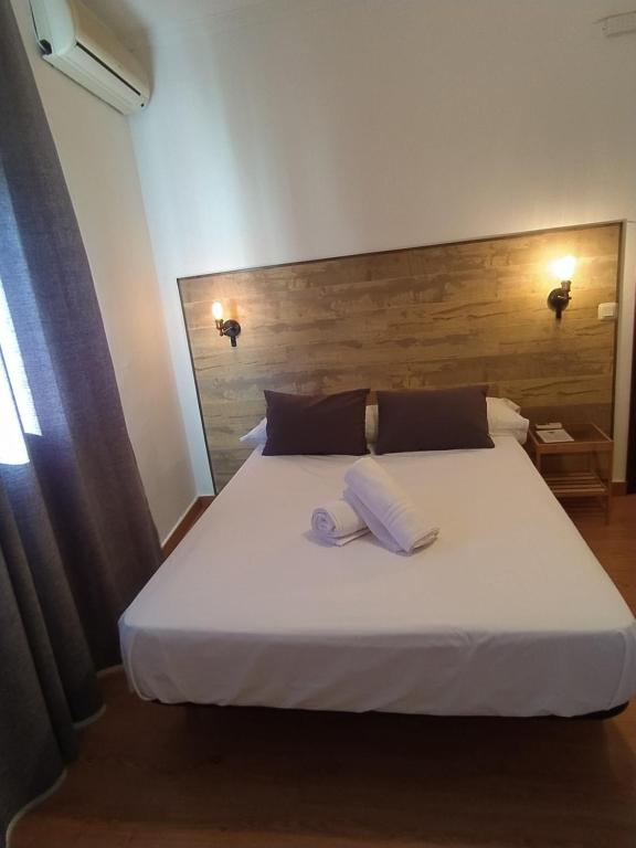 蒙地卡罗Hostal El Pinar的卧室配有白色的床和2条毛巾