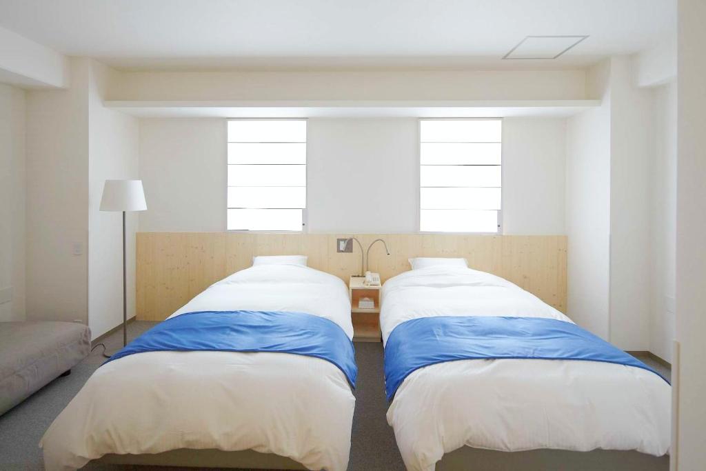 大阪Shin-Osaka Station Hotel的带2扇窗户的客房内的2张床