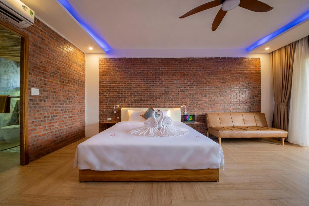 会安Hoi An Golden Bamboo An Bang Beach Villa & Spa的一间卧室设有一张床和砖墙