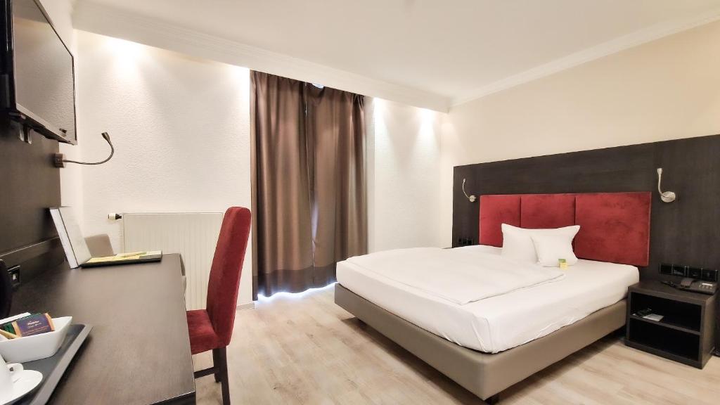 瓦尔多夫杜密兹尔奥斯特里斯酒店的卧室配有白色的床和红色床头板