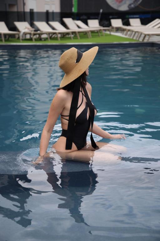 布克维Premium hotel & SPA的坐在游泳池的戴帽子的女人