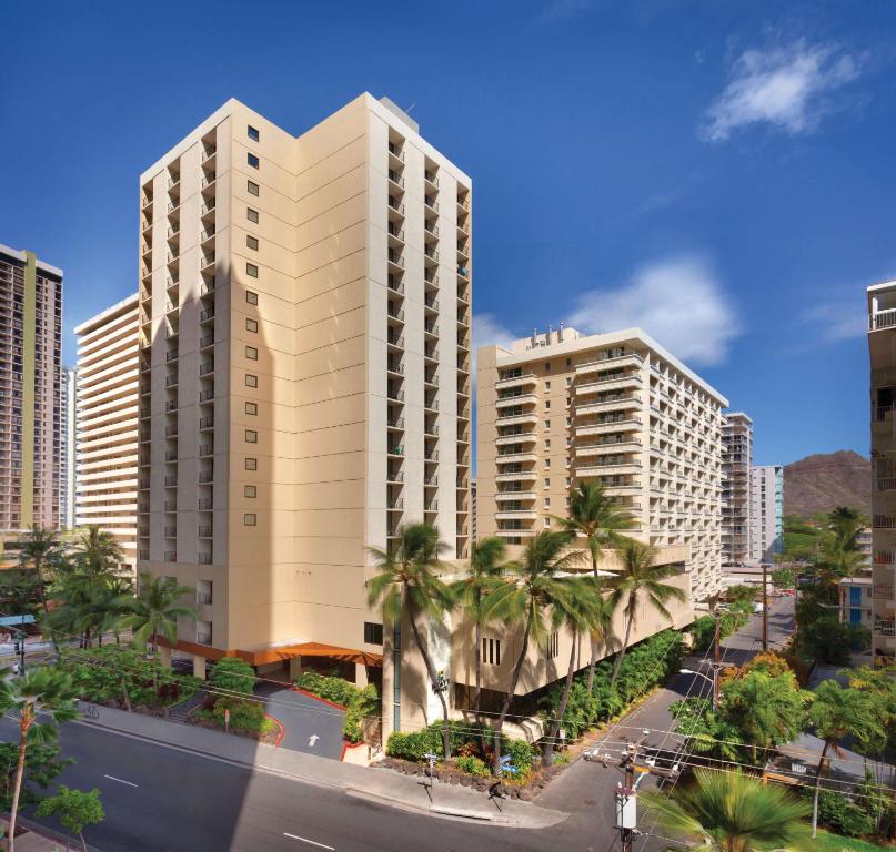 檀香山Hyatt Place Waikiki Beach的一座高大的白色建筑,在城市里种有棕榈树