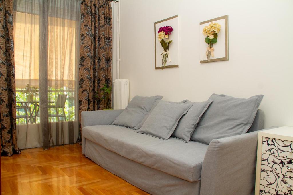 雅典Athens Quality Apartments - No4 - 1-bedroom apartment的客厅配有沙发,墙上挂着鲜花