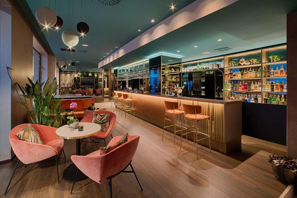 米兰NH Collection Milano Touring的一间带粉色椅子的餐厅和一间酒吧
