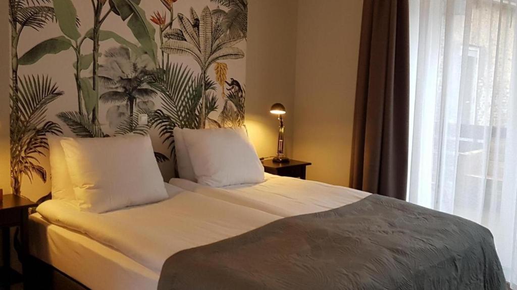 哈林亨Anna's Zusje Boetiekhotel的卧室配有一张铺有白色床单的床,墙上挂着植物
