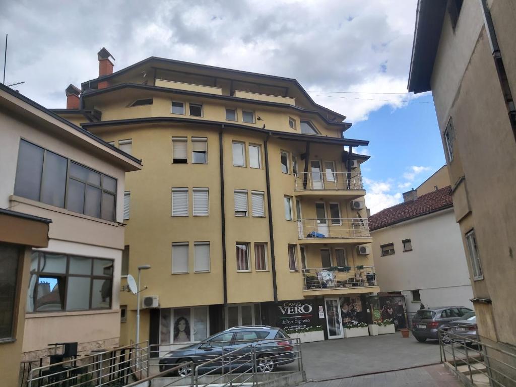 弗拉涅Vranje City Center, Penthouse Delux Apartment的一座黄色的建筑,前面有一辆汽车