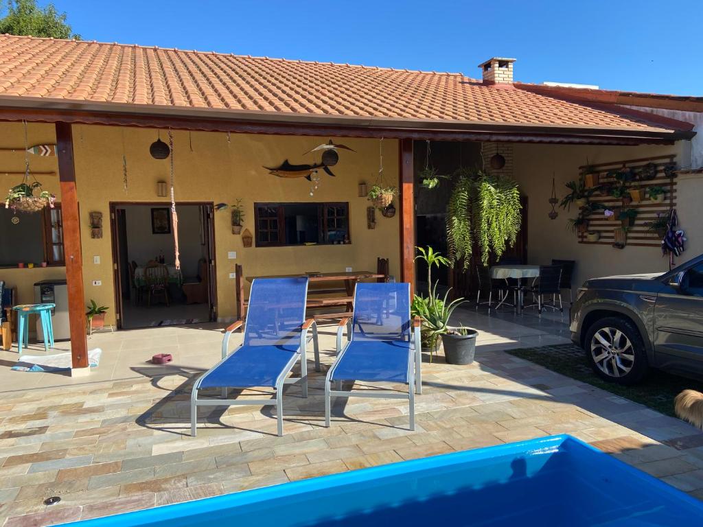朱奎casa 300 mts da praia的两把蓝色的椅子和一张桌子,位于房子前面