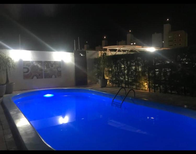 莫索罗Apartamento em Mossoró的一座蓝色的游泳池,晚上与大楼相连