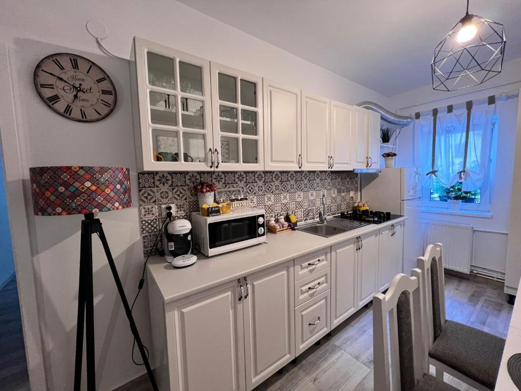 普雷代亚尔Sweet Home Apartament的厨房配有白色橱柜和墙上的时钟