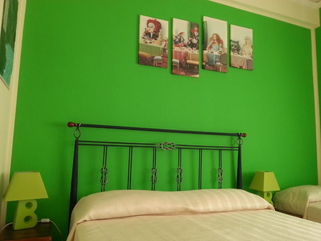 特拉帕尼因特拉巴托洛住宿加早餐旅馆的一间绿色卧室,配有一张床和四张墙上的照片