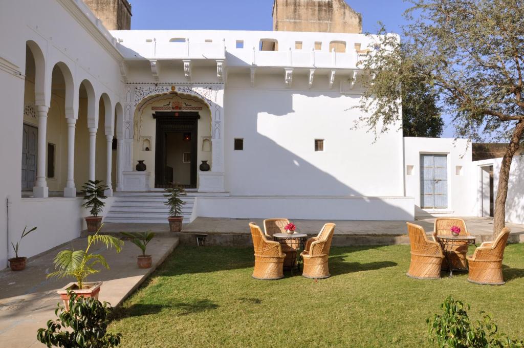 曼达瓦Hotel Chobdar Haveli的建筑前的院子,配有桌椅