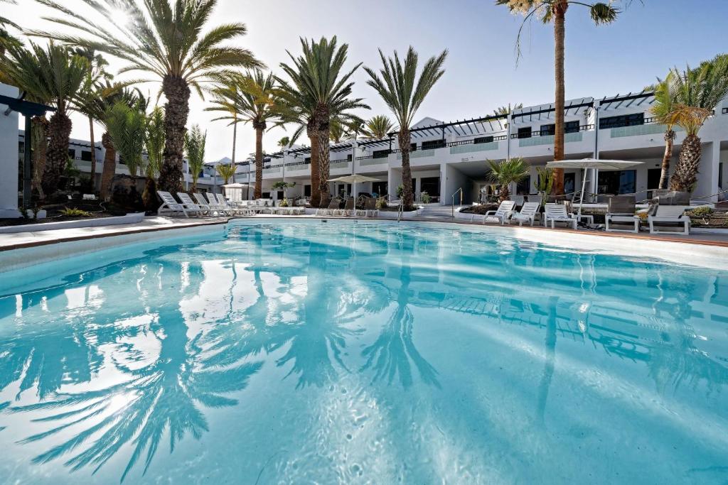 卡门港拉布兰达海滩俱乐部公寓的一座棕榈树大型游泳池和一座建筑