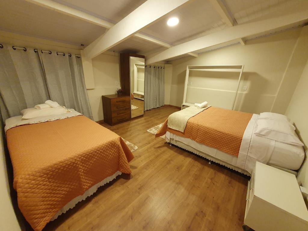 塞拉内格拉Villa Ida Acomodações, 3 suítes aconchegantes e charmosas no centro的配有两张床的客房铺有木地板。