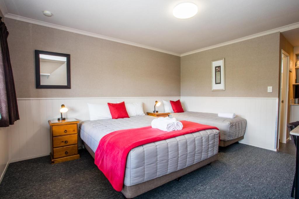 蒂阿瑙Te Anau Top 10 Holiday Park and Motels的一间卧室配有两张带红白色枕头的床