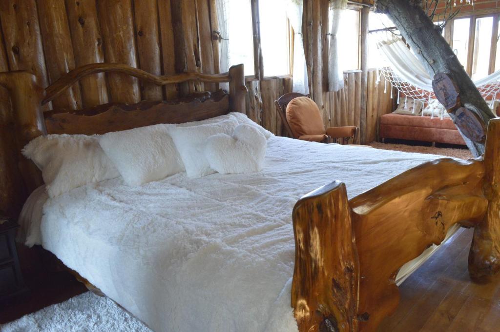 基多Treehouse Gastro Hotel的一间卧室配有一张大木床和白色床单