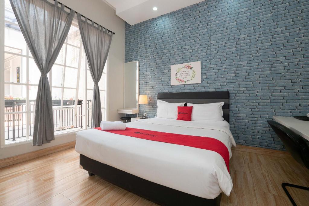 雅加达RedDoorz Premium near RS Pondok Indah La Maison的一间卧室设有一张大床和砖墙